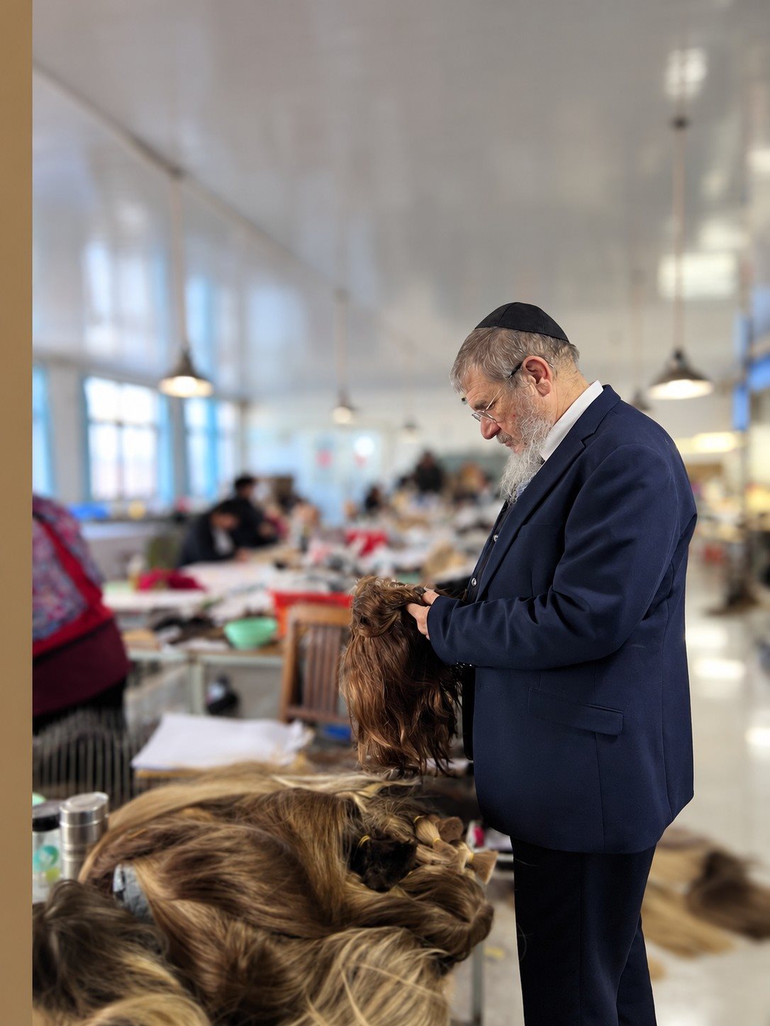 A supervising rabbi checking a finished sheitel on the production floor
